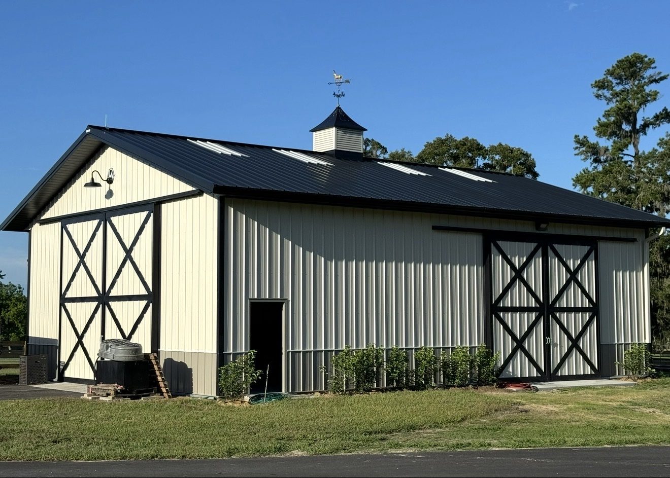 Cream-colored horse barn with a cupola in a fenced pasture fitted with lightning protection